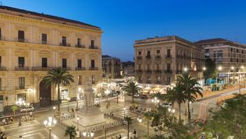 Una plaza histórica con arquitectura clásica, un monumento central y palmeras.