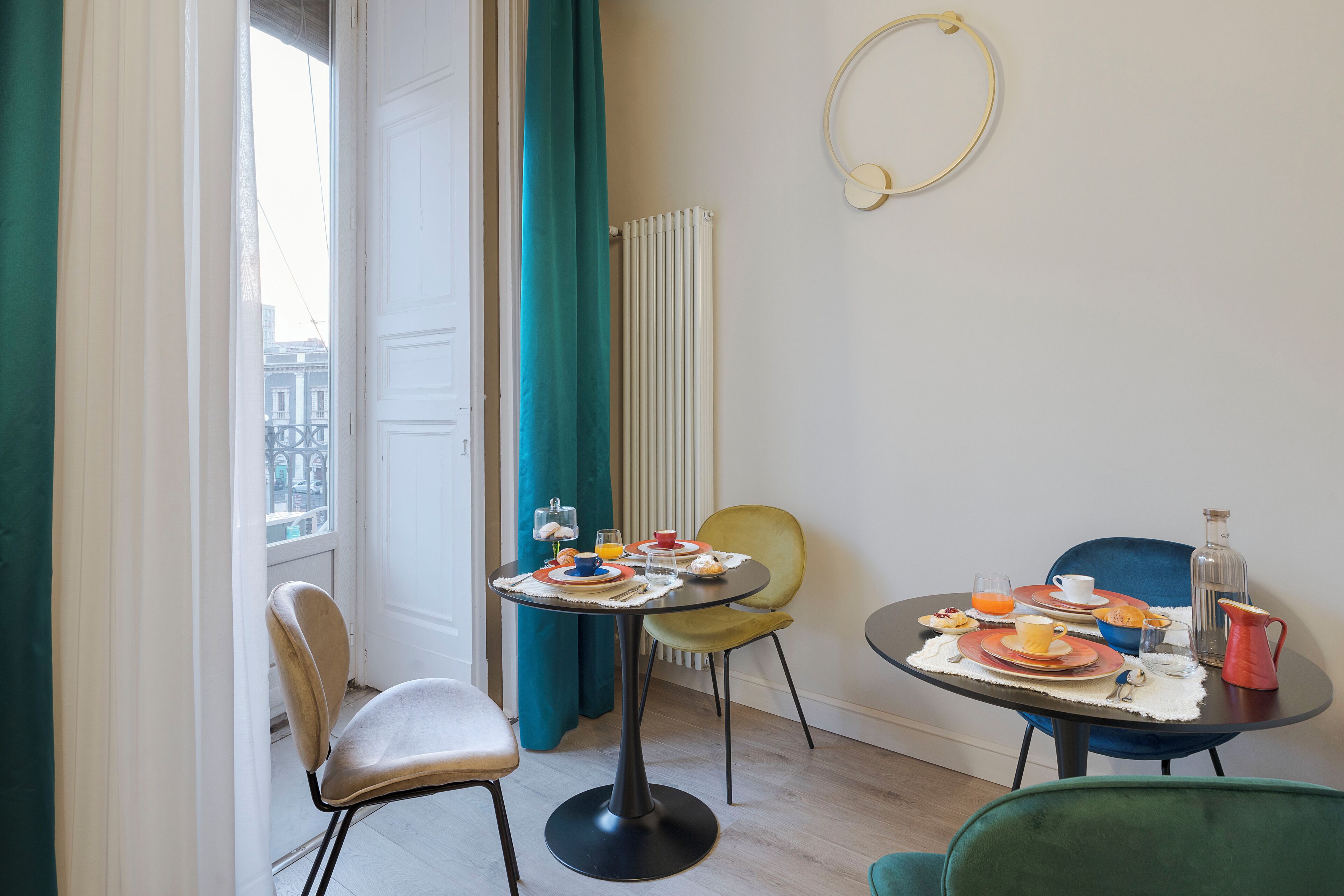 Un comedor con una mesa dispuesta para el desayuno, dos sillas, un radiador y vistas a edificios.