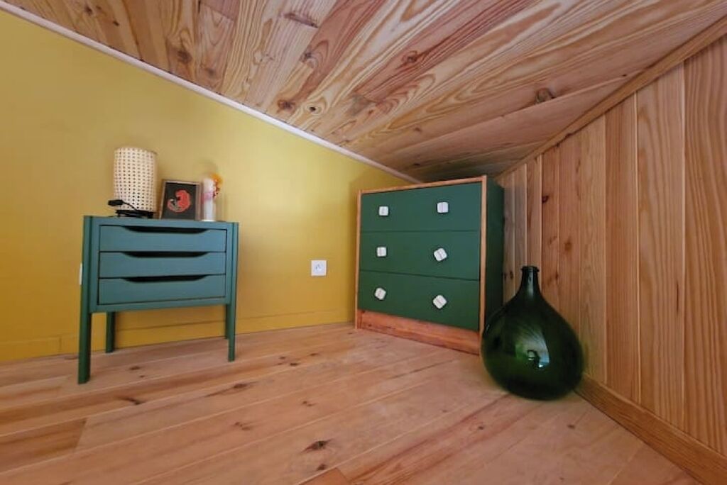 Ein Zimmer mit Holzboden, einem Türkis-Anzugsschrank, einem grünen Aktenschrank und einer grünen Vase.