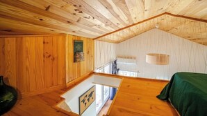 A cabin interior with wooden walls, a loft area, and a bed with a green cover. - Cottage in the countryside - A haven of peace in Provence Verte [LA K-LINE] [LA K-LINE (Entrecasteaux)