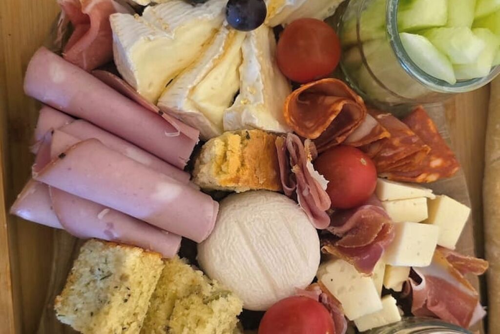 Un tagliere con salumi, formaggi e verdure assortiti.