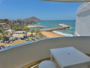 A balcony with a view of a beach, a parking area, and buildings in the background. - Yatch Apartments (Mazatlán)