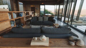 Ein modernes Wohnzimmer mit einem dunkelgrauen Sofa, Holzböden und einem großen Fenster mit Blick auf die Landschaft.