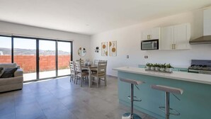 Una cucina moderna con mobili bianchi, una cappa in acciaio inossidabile e un’area bar con sgabelli.
