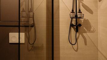 A modern bathroom with a glass-enclosed shower, a toilet, and a mirror.