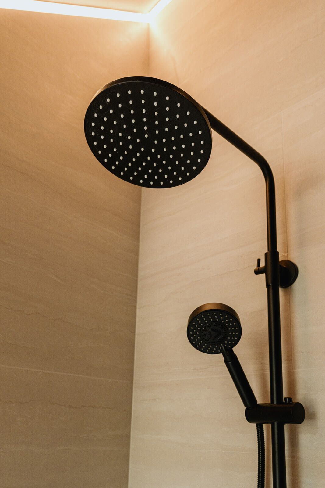 A shower with a round head and a handheld attachment.