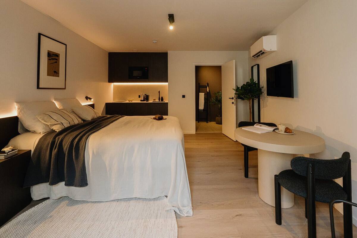 Une chambre moderne avec un lit, une table de chevet et un petit espace bureau avec une chaise.