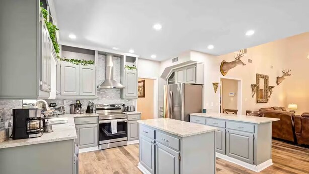 Una cocina moderna con gabinetes grises, electrodomésticos de acero inoxidable y una isla central.
