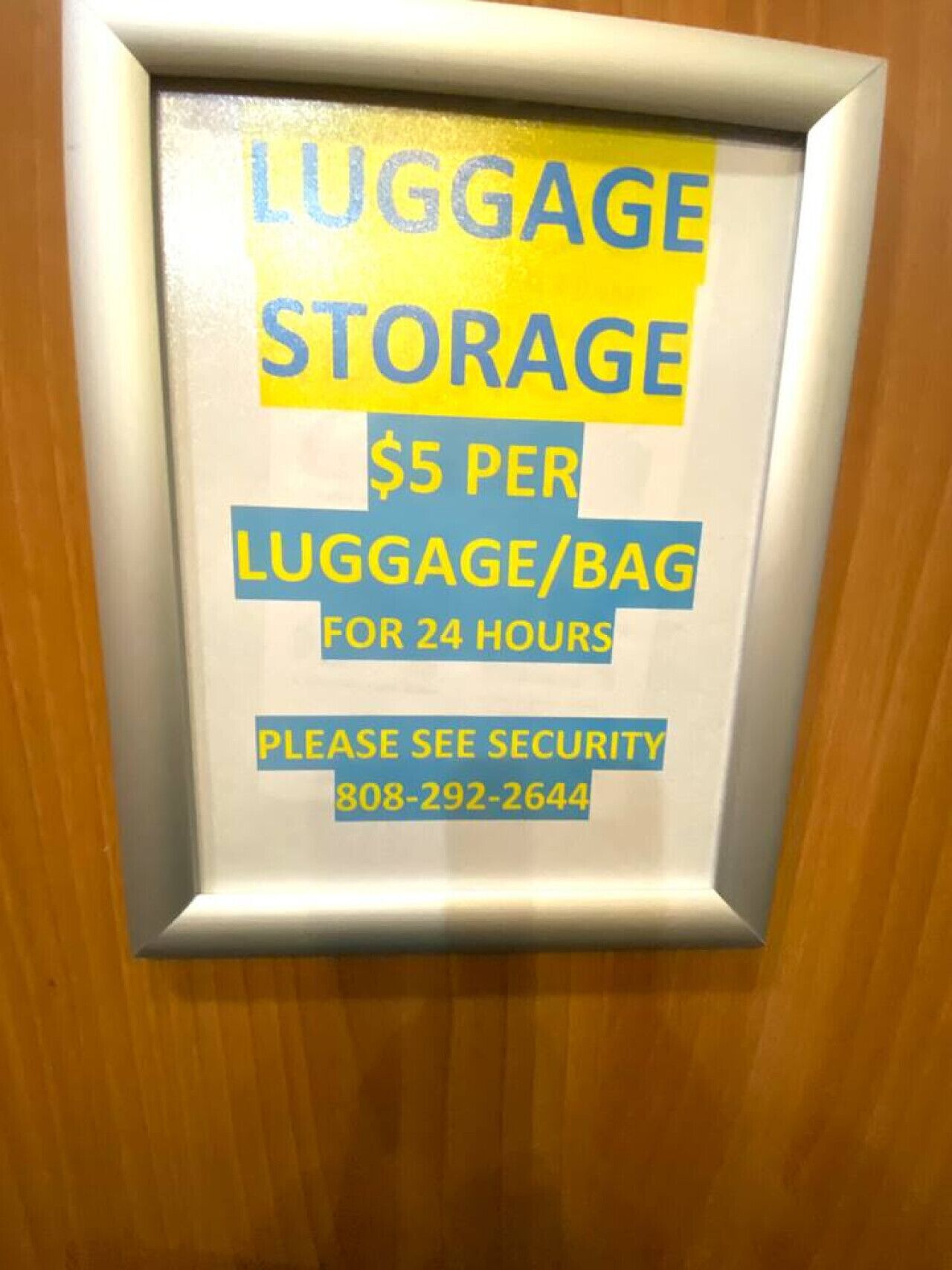 Ein gerahmtes Schild bietet Gepäckaufbewahrung für 5 Dollar pro Tasche für 24 Stunden, inklusive Angabe einer Sicherheits-Kontaktnummer.