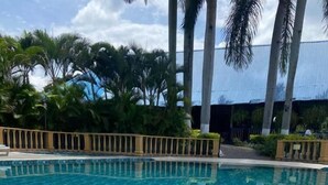 A clear blue pool with tiled flooring, surrounded by palm trees and a fence. - Hotel San Antonio del Cerro (Pereira)