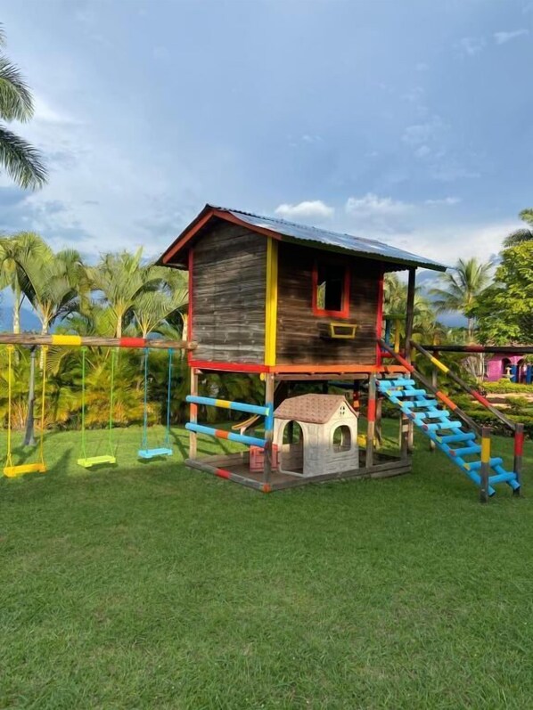 A wooden playhouse with a red roof and a small doghouse attached. - Hotel San Antonio del Cerro (Pereira)