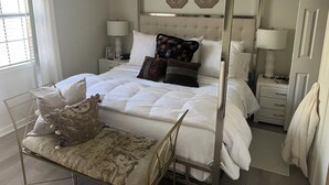 A four-poster bed with white bedding and decorative pillows, a bedside table with a lamp, and a window with curtains. - Walk to the Grove!From this 3BR 2 Bath!! (Oxford)