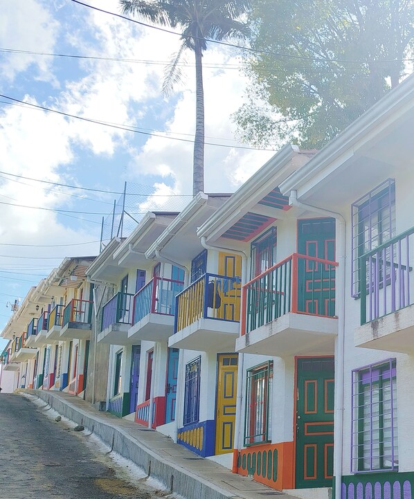 Un filare di edifici residenziali colorati con balconi e una palma sullo sfondo.