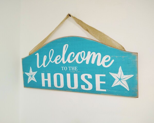 A turquoise welcome sign with white lettering and star decorations.