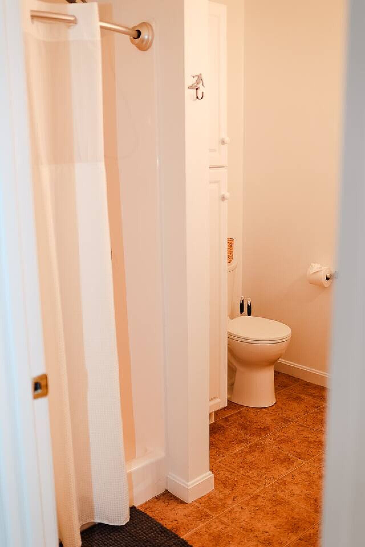Um banheiro com vaso sanitário, cortina de chuveiro e porta-toalhas.