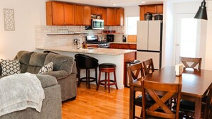 Una cocina moderna con armarios de madera, una isla central y una zona de comedor con mesa y sillas.