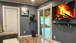 A living room with a fireplace, a television, a door, and a plant. - Wonderful 3-bedroom house in St. Augustine, close to beach and Historic District (St. Augustine)