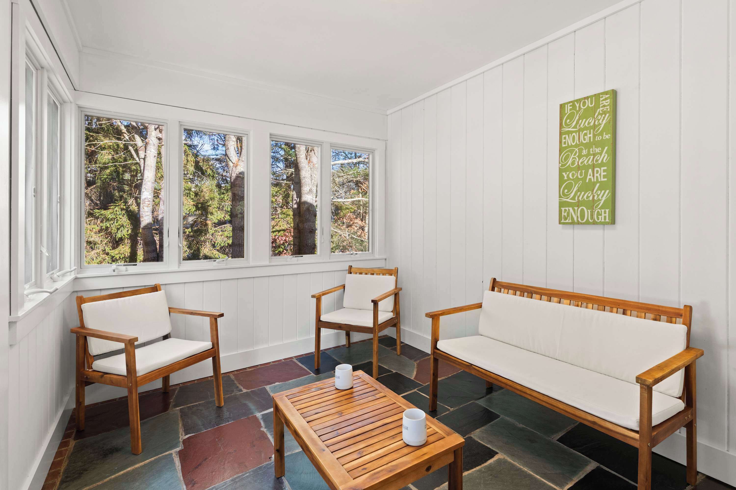A room with a wooden bench, two chairs, and a table with two cups.