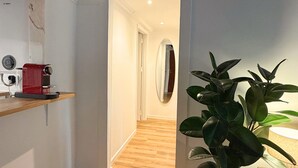 A hallway with wooden flooring, a red espresso machine, a mirror, and a potted plant. - Arroios Elegance Residence - Lisbon Center (Lisboa)