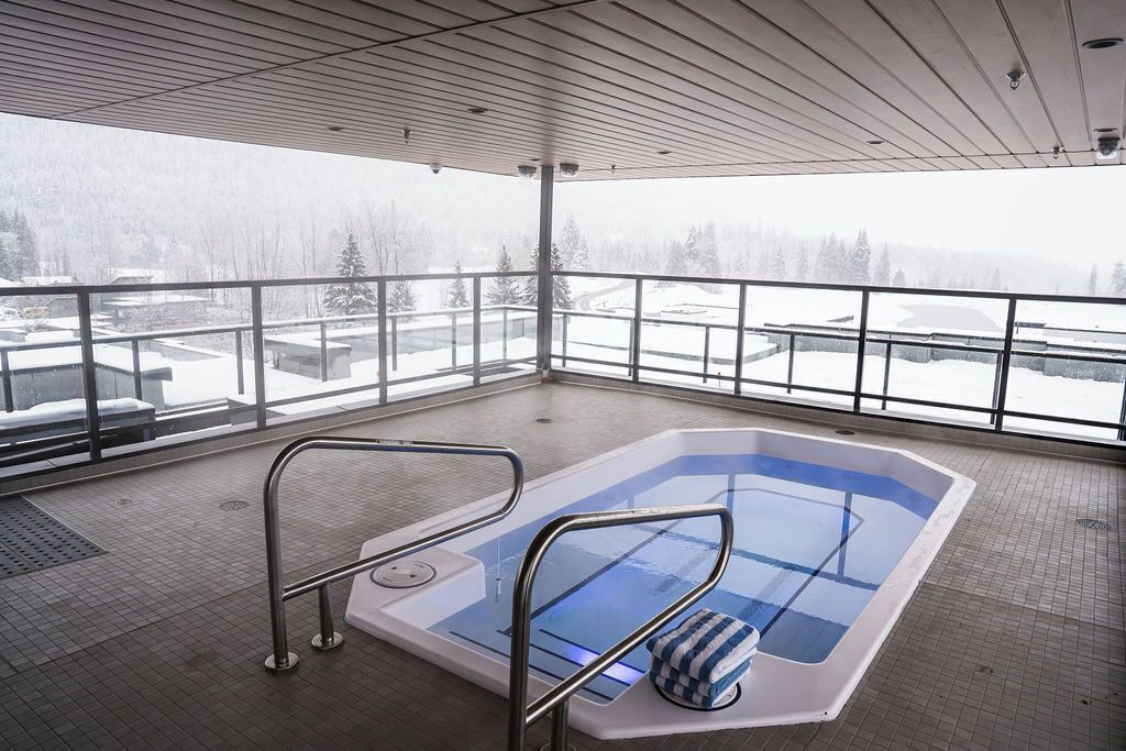 A heated indoor swimming pool with a view of a snowy landscape.