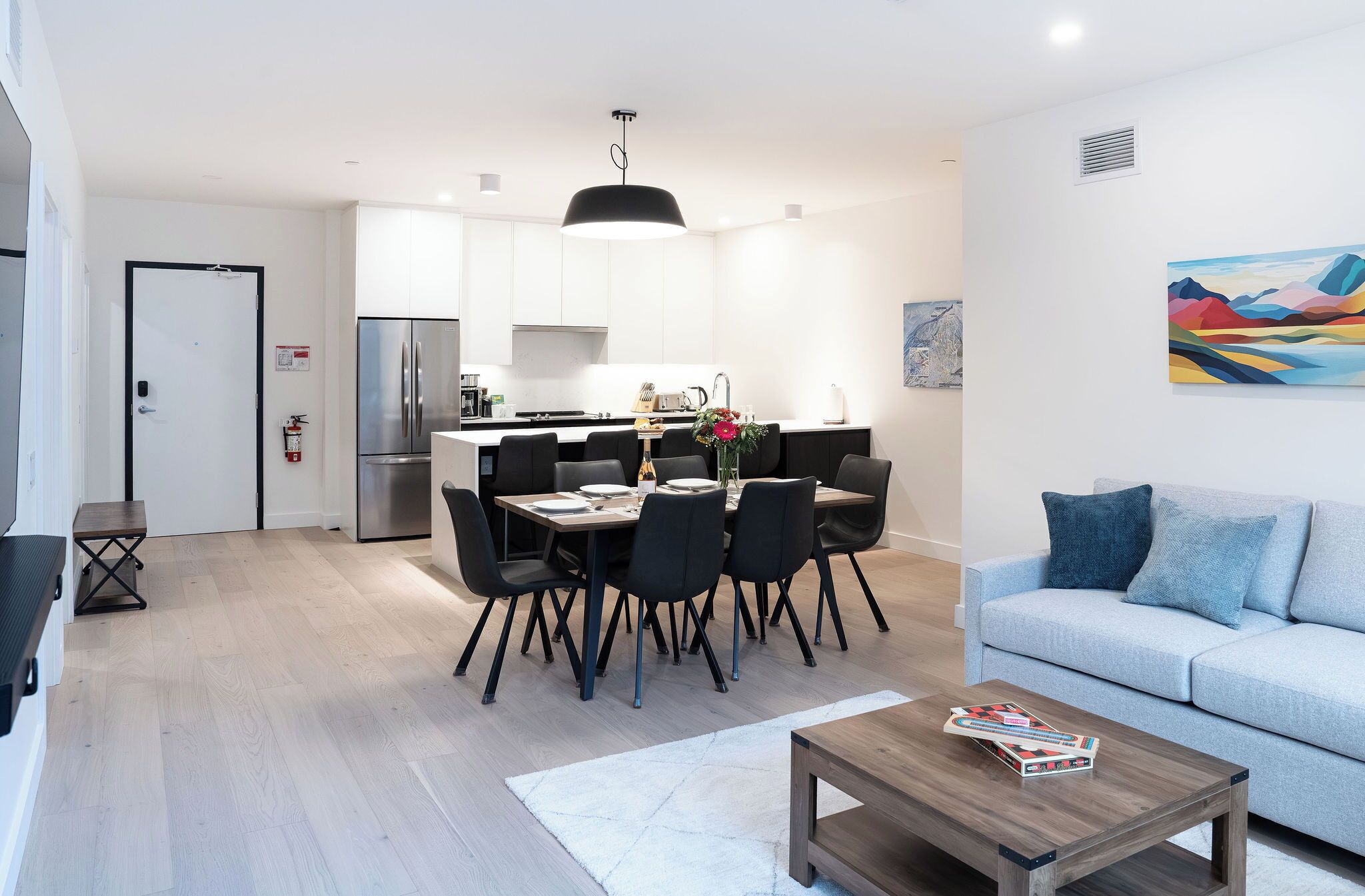 A modern apartment with a dining area, kitchen, and living room.