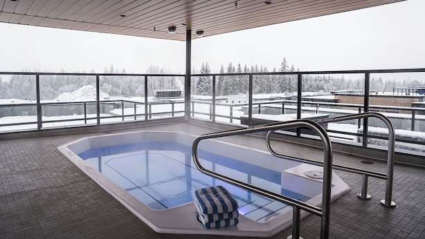 A heated indoor swimming pool with a view of snow-covered trees and buildings. - Bluebird by Revelstoke Vacations (Revelstoke)
