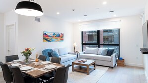 A modern living room with a dining area, a sofa set, a coffee table, and a painting on the wall. - Bluebird by Revelstoke Vacations (Revelstoke)