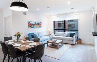 Una sala de estar moderna con comedor, un conjunto de sofá, una mesa de centro y un cuadro en la pared.