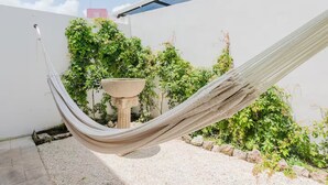 A hammock in a garden area with a stone planter and lush greenery. - Beautiful, cozy & comfortable house Puerto Morelos (Puerto Morelos)