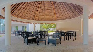 An outdoor seating area with thatched roofing and multiple tables and chairs. - Premium Celebrity home private pool Puerto Morelos (Puerto Morelos)