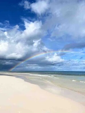 Uma praia com um arco-íris visível sobre o oceano.