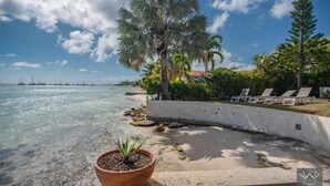 A beach with a curved concrete wall, lounge chairs, and a potted plant. - Montepulciano (Saint François)