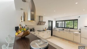 A modern kitchen with a central island, stainless steel appliances, and a large window providing natural light. - Montepulciano (Saint François)