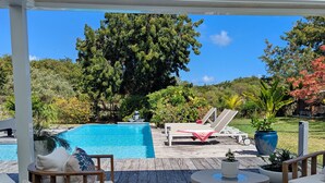 A covered outdoor area with a pool, lounge chairs, and a dining table. - Rubis |Exclusivité (Saint François)
