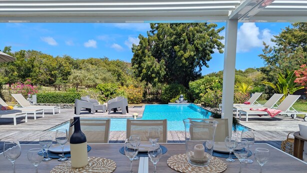 A poolside dining area with a view of a swimming pool, surrounded by lounge chairs and a lush garden. - Rubis |Exclusivité (Saint François)