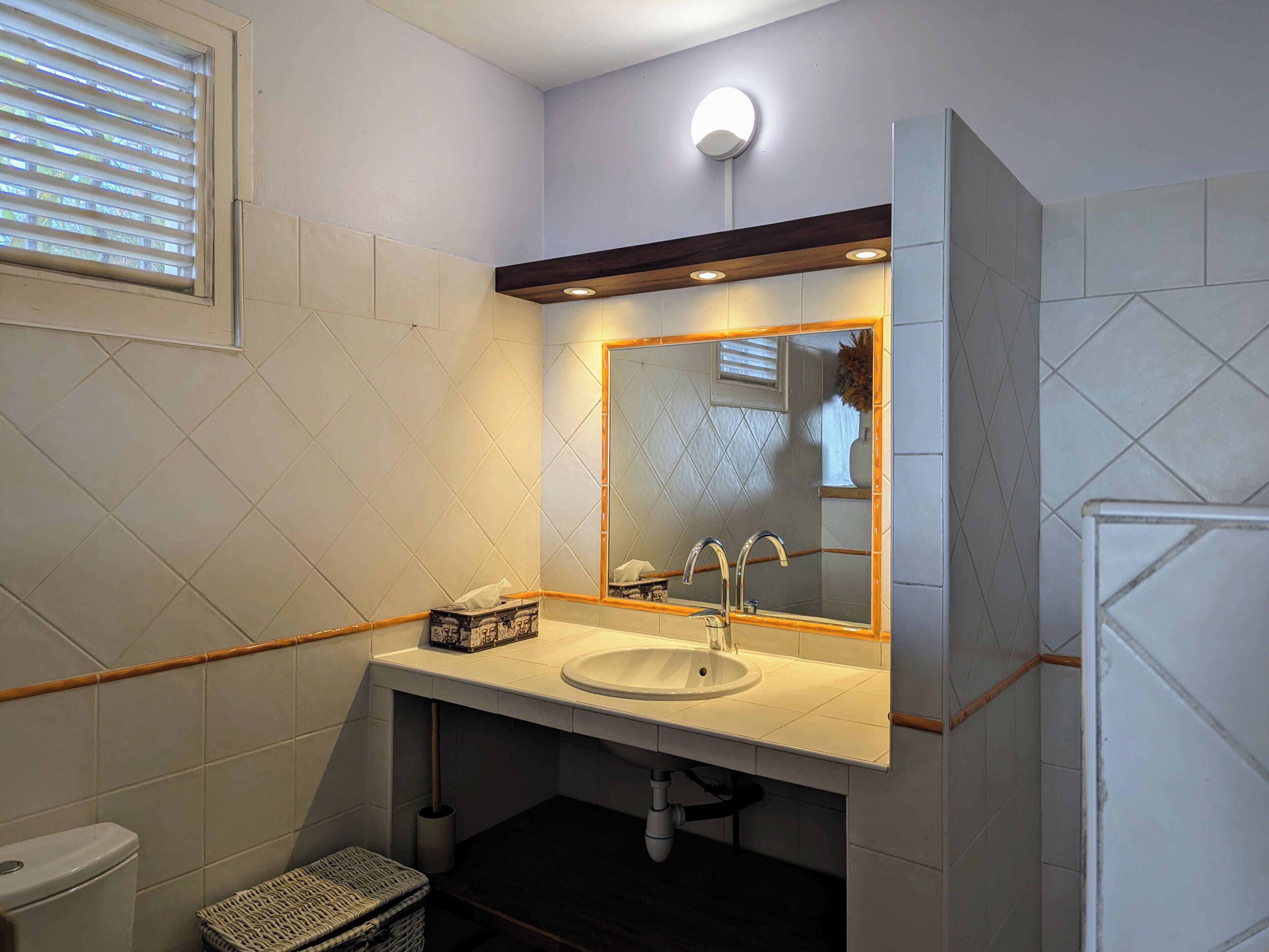 A bathroom with a white sink, a mirror, and a toilet.