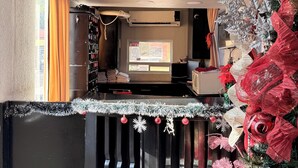 A room with a black-framed window, a clock on the wall, and a Christmas tree with red and white decorations. - Hotel Villa Jardín (Matamoros)