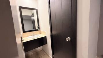 A bathroom with a dark wooden door, a white sink, and a mirror above it.