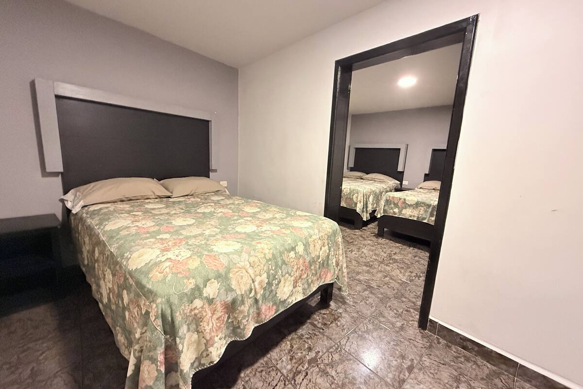 Un dormitorio con cama, un espejo grande y cabecera.