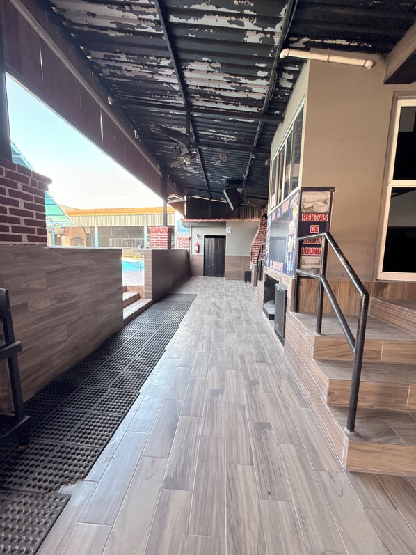 A corridor with a tiled floor, a metal staircase, and a brick wall.