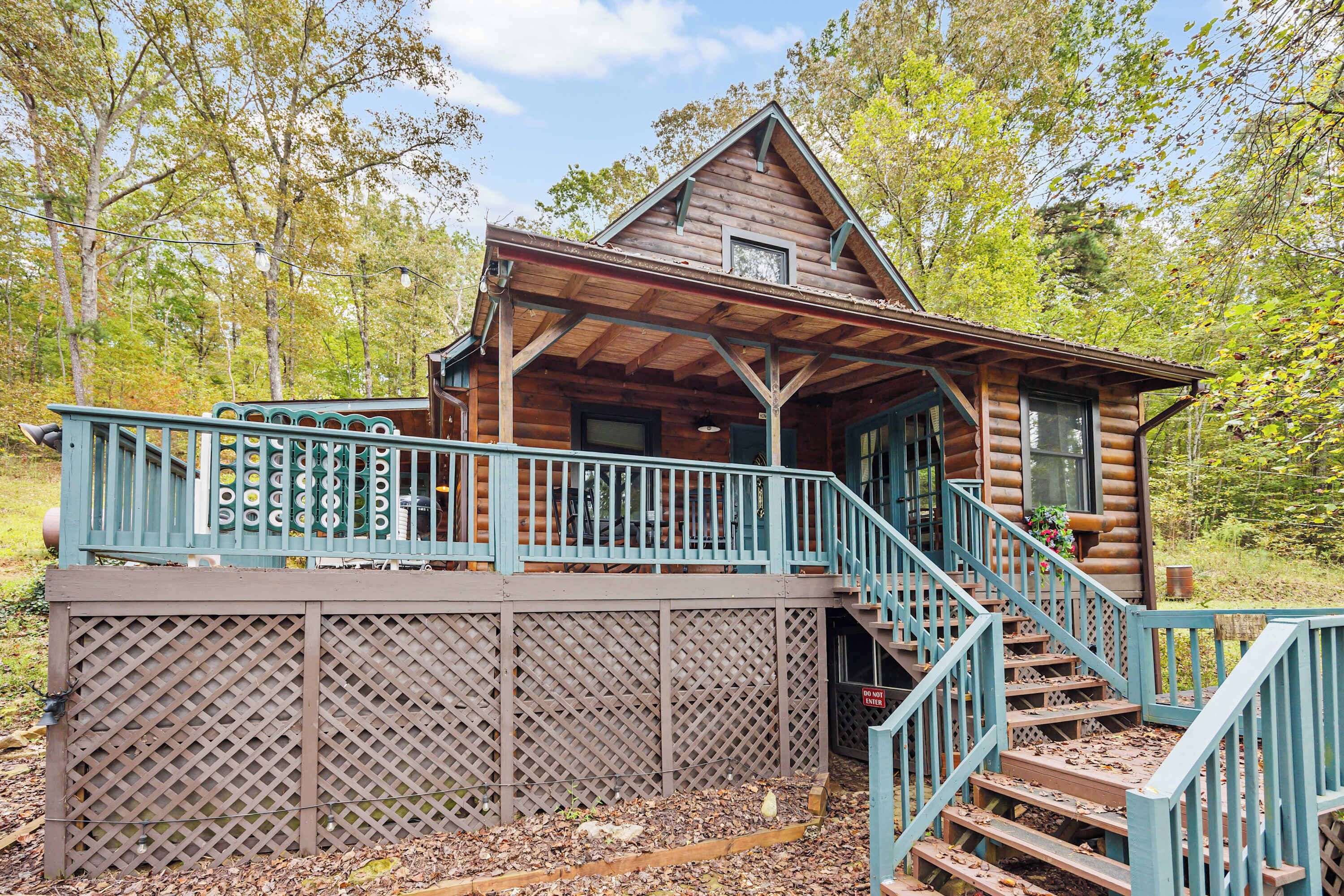 A log cabin with a wooden deck and stairs leading to a porch.