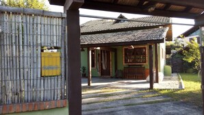 A traditional house with a tiled roof, a wooden porch, and a bamboo fence. - Located 300 meters from the beach, the house faces east and is surrounded by grass. (Florianópolis)