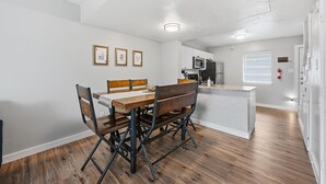 A dining area with a wooden table and chairs, a kitchen with white cabinets, and a small island with a microwave. - Family, Business & Game-Day Getaway • Close to Arlington Attractions • Sleeps 8 (Arlington)