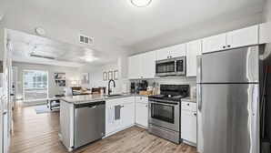 A modern kitchen with white cabinets, stainless steel appliances, and a wooden floor. - Family, Business & Game-Day Getaway • Close to Arlington Attractions • Sleeps 8 (Arlington)
