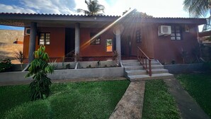 A two-story house with a red exterior, a covered porch, and a staircase leading to the entrance. - Quinta Aqua Di Mar Playa Las Hojas (Playa Las Hojas)