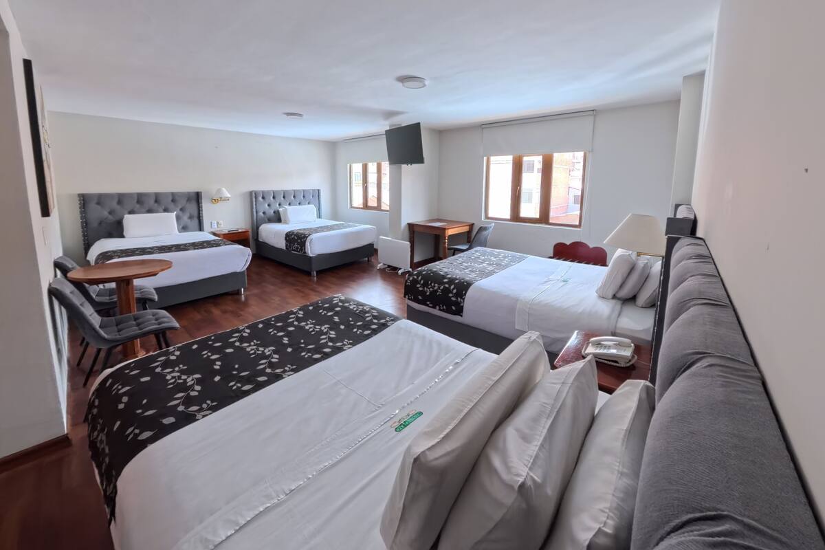 A hotel room with two beds, a sofa, a small table, and a chair.