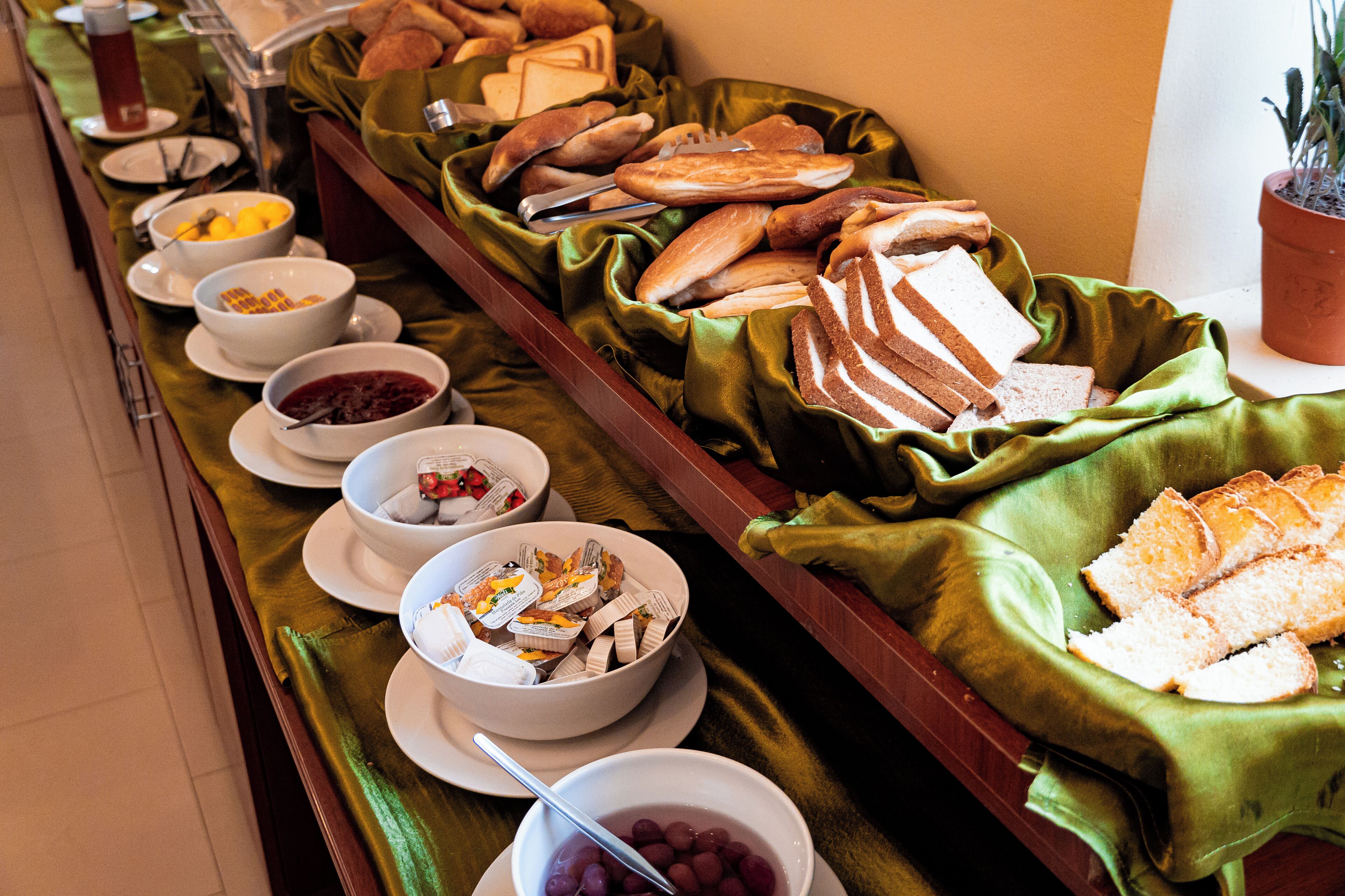 A buffet with various food items and bowls of fruit.