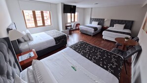 A hotel room with two single beds, a sofa, a small table, and a TV. - Casona Puno (Puno)