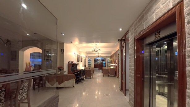 A hotel corridor with a reception desk, seating area, and a glass elevator. - Casona Puno (Puno)