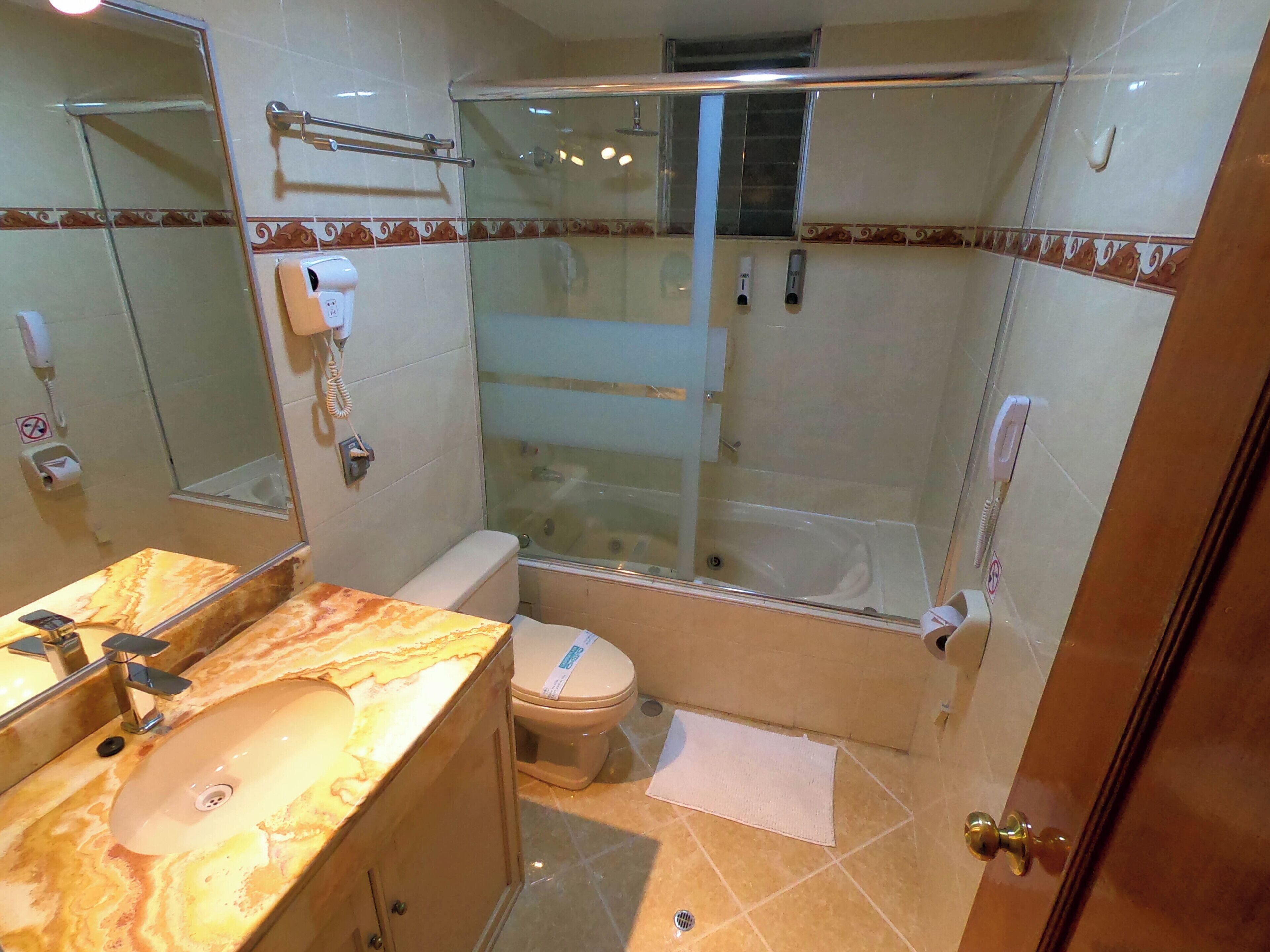 A bathroom with a marble sink, toilet, and glass-enclosed shower.